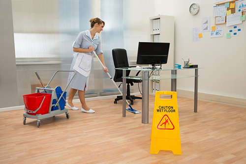 Young Maid Cleaning Floor With Mop In Office